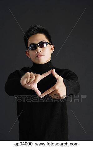 Young man dressed in black, wearing sunglasses, standing against black background View Large Photo Image Stock Image - Young man dressed in black, wearing sunglasses, standing against black background. Fotosearch