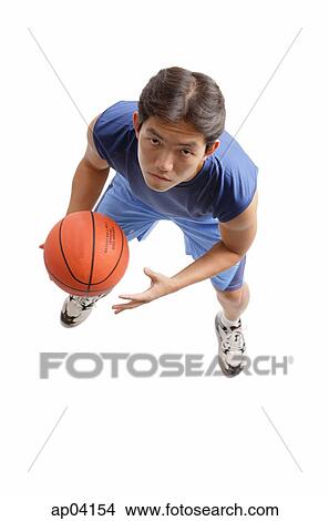 Young man holding basketball, looking up at camera View Large Photo Image Picture - Young man holding basketball, looking up at camera. Fotosearch