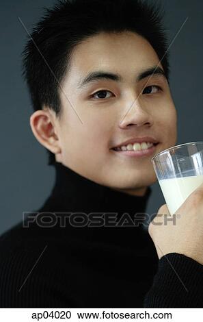Stock Image - Young man holding glass of milk . Fotosearch
