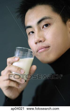 Young man holding glass of milk, looking at camera View Large Photo Image Stock Image - Young man holding glass of milk, looking at camera . Fotosearch