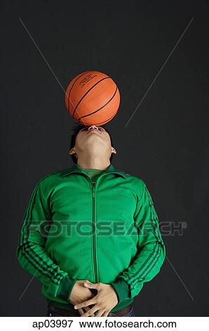 Young man in green jacket balancing basketball on nose View Large Photo Image Stock Photo - Young man in green jacket balancing basketball on nose . Fotosearch