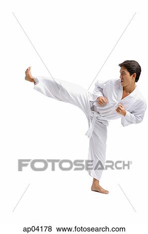 Young man practicing martial arts uniform, kicking with one leg View Large Photo Image Stock Photo - Young man practicing martial arts uniform, kicking with one leg . Fotosearch