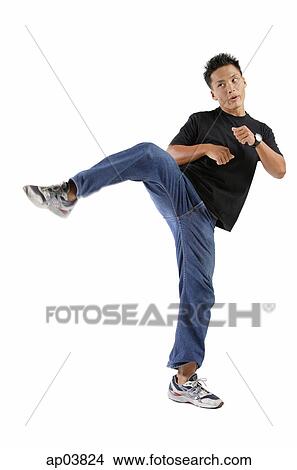 Picture - Young man standing on one leg, kicking. Fotosearch