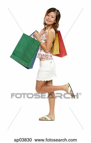 Young woman carrying shopping bags, standing on one leg View Large Photo Image Stock Image - Young woman carrying shopping bags, standing on one leg. Fotosearch