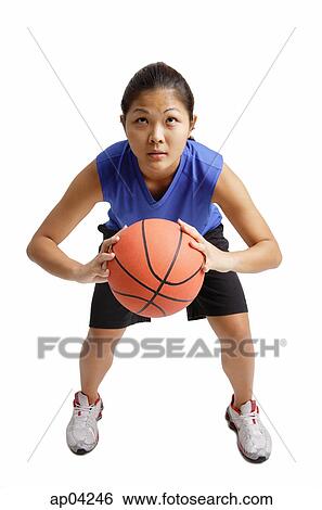 Stock Photograph - Young woman holding basketball, aiming for a hot. Fotosearch