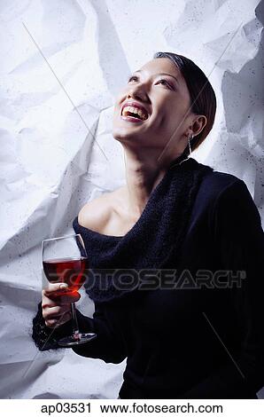 Young woman in black top, holding wine glass, looking up, smiling View Large Photo Image Stock Image - Young woman in black top, holding wine glass, looking up, smiling. Fotosearch