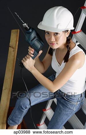 Young woman in hard hat, holding drill, sitting on ladder View Large Photo Image Stock Photo - Young woman in hard hat, holding drill, sitting on ladder . Fotosearch