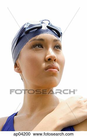 Stock Image - Young woman in swimming cap, head shot. Fotosearch