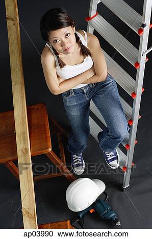Young woman sitting on ladder, arms crossed, looking at camera View Large Photo Image Stock Image - Young woman sitting on ladder, arms crossed, looking at camera . Fotosearch