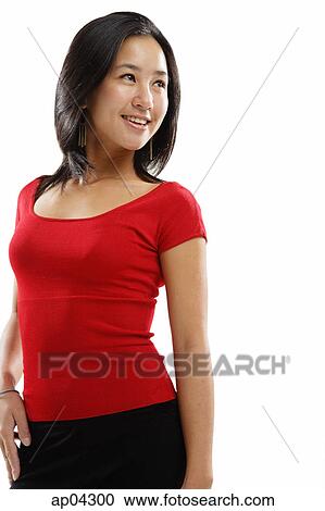 Stock Image - Young woman standing and smiling, looking away. Fotosearch