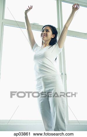 Stock Image - Young woman standing and stretching. Fotosearch