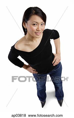 Stock Photo - Young woman standing with hands on hip looking at camera . Fotosearch