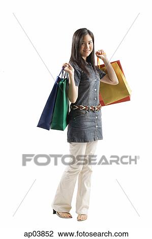 Stock Image - Young woman standing with shopping bags, looking at camera . Fotosearch