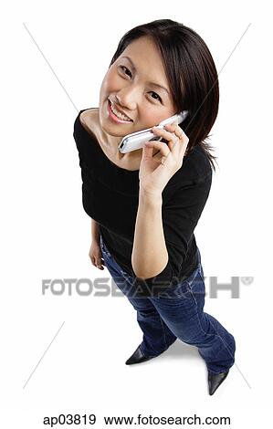 Stock Photo - Young woman using mobile phone, looking at camera . Fotosearch
