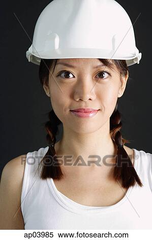 Stock Photography - Young woman wearing hard hat. Fotosearch