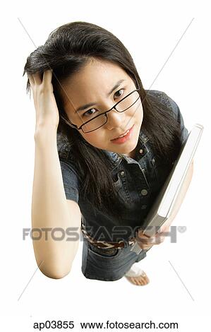 Young woman with glasses, carrying book, scratching hair View Large Photo Image Stock Photography - Young woman with glasses, carrying book, scratching hair . Fotosearch