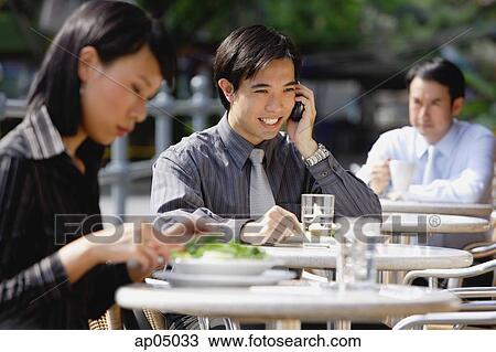 Business people at outdoor café, focus on man using mobile phone View Large Photo Image Stock Image - Business people at outdoor café, focus on man using mobile phone. Fotosearch