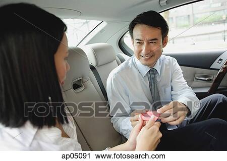 Businessman and businesswoman in backseat of car, exchanging business cards View Large Photo Image Stock Image - Businessman and businesswoman in backseat of car, exchanging business cards. Fotosearch