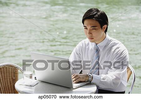 Businessman at outdoor cafe, using laptop, river in the background View Large Photo Image Stock Image - Businessman at outdoor cafe, using laptop, river in the background. Fotosearch