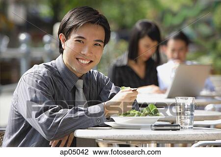 Businessman having lunch at outdoor cafe, smiling at camera View Large Photo Image Stock Image - Businessman having lunch at outdoor cafe, smiling at camera. Fotosearch