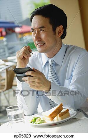 Businessman in cafe, using PDA, smiling View Large Photo Image Stock Photo - Businessman in cafe, using PDA, smiling. Fotosearch