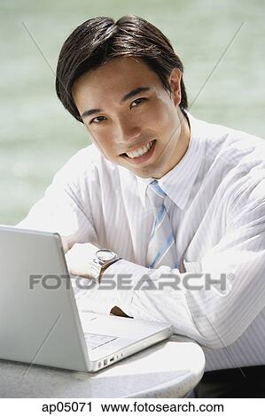 Businessman sitting at outdoor cafe, arms crossed, laptop in front of him View Large Photo Image Stock Image - Businessman sitting at outdoor cafe, arms crossed, laptop in front of him. Fotosearch