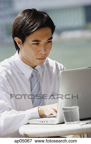 Businessman sitting at outdoor cafe, using laptop View Large Photo Image Stock Photo - Businessman sitting at outdoor cafe, using laptop. Fotosearch