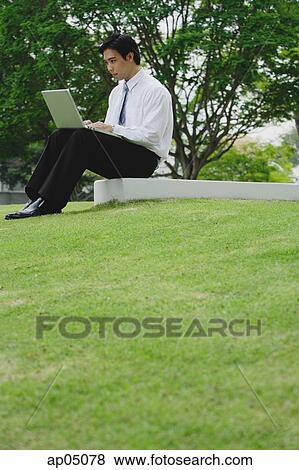 Businessman sitting in park using laptop View Large Photo Image Stock Photo - Businessman sitting in park using laptop. Fotosearch