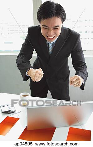 Businessman standing, looking at laptop, making a face View Large Photo Image Stock Photography - Businessman standing, looking at laptop, making a face. Fotosearch