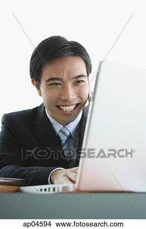 Picture - Businessman using laptop and mobile phone. Fotosearch