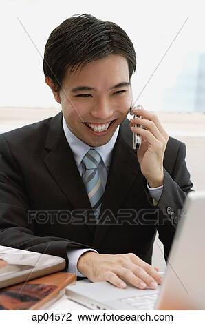 Businessman using mobile phone and laptop, smiling View Large Photo Image Stock Image - Businessman using mobile phone and laptop, smiling. Fotosearch