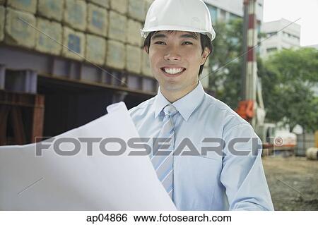 Businessman with blueprints, smiling at camera View Large Photo Image Stock Photograph - Businessman with blueprints, smiling at camera. Fotosearch