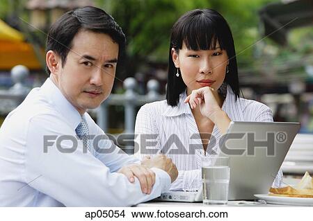 Businesswoman and businessman at outdoor cafe, looking at camera View Large Photo Image Picture - Businesswoman and businessman at outdoor cafe, looking at camera. Fotosearch
