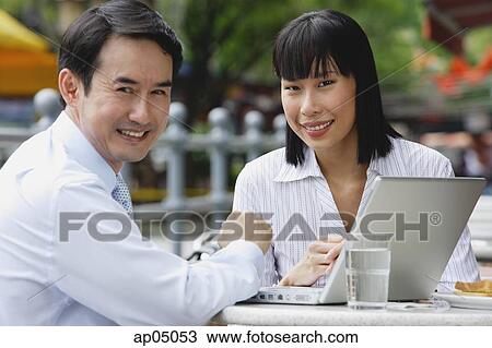 Businesswoman and businessman at outdoor cafe, with laptop, smiling at camera View Large Photo Image Stock Image - Businesswoman and businessman at outdoor cafe, with laptop, smiling at camera. Fotosearch