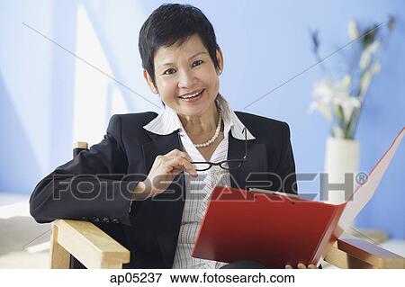 Businesswoman holding clipboard and glasses, smiling at camera View Large Photo Image Stock Photo - Businesswoman holding clipboard and glasses, smiling at camera. Fotosearch