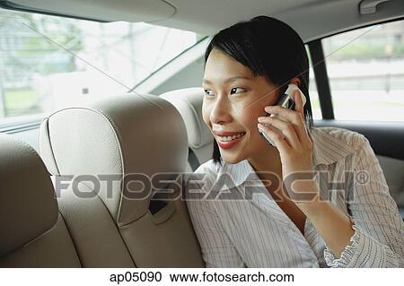 Businesswoman in backseat of car using mobile phone, smiling View Large Photo Image Stock Image - Businesswoman in backseat of car using mobile phone, smiling. Fotosearch
