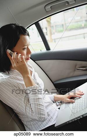 Stock Photo - Businesswoman in car on the phone and using laptop. Fotosearch