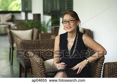 Businesswoman sitting in patio, looking at camera View Large Photo Image Stock Photography - Businesswoman sitting in patio, looking at camera. Fotosearch