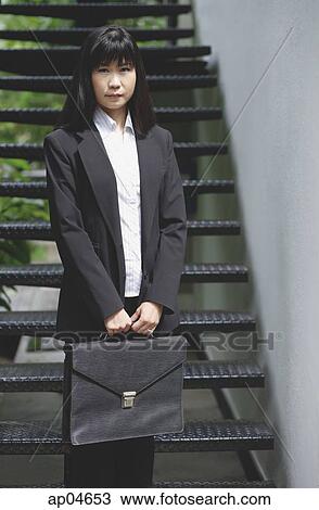 Stock Image - Businesswoman standing with briefcase. Fotosearch