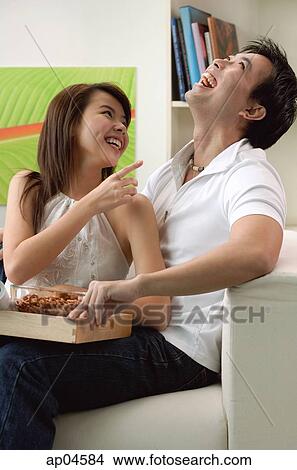 Couple at home in living room, sitting on sofa, laughing View Large Photo Image Picture - Couple at home in living room, sitting on sofa, laughing. Fotosearch