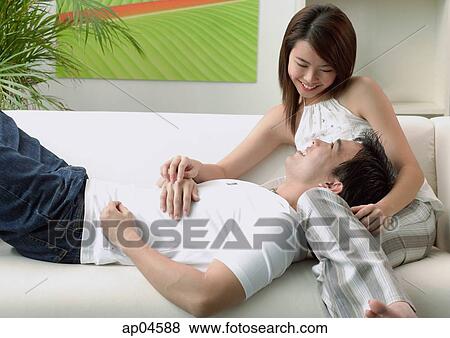 Stock Photo - Couple at home, man lying on woman's lap. Fotosearch