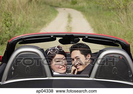 Couple in convertible sports car, turning to look at camera View Large Photo Image Stock Photo - Couple in convertible sports car, turning to look at camera. Fotosearch