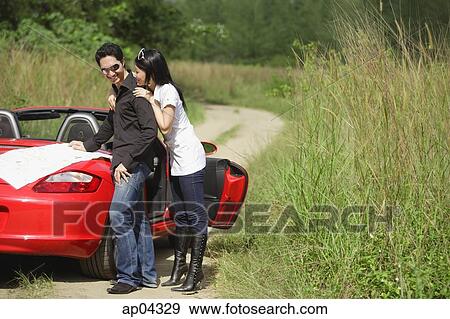Couple standing next to red sports car, map on the car View Large Photo Image Stock Photo - Couple standing next to red sports car, map on the car. Fotosearch