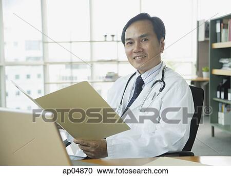 Doctor sitting in office, smiling at camera View Large Photo Image Stock Image - Doctor sitting in office, smiling at camera. Fotosearch
