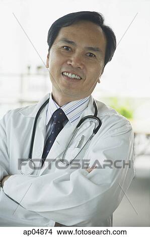 Doctor smiling at camera, arms crossed View Large Photo Image Picture - Doctor smiling at camera, arms crossed. Fotosearch