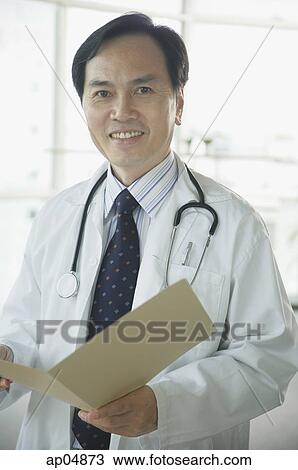 Doctor smiling at camera, holding folder View Large Photo Image Stock Image - Doctor smiling at camera, holding folder. Fotosearch