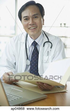 Doctor smiling at camera, holding folder View Large Photo Image Stock Photo - Doctor smiling at camera, holding folder. Fotosearch