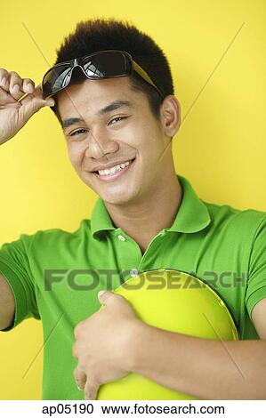Man carrying helmet, adjusting sunglasses, looking at camera View Large Photo Image Stock Image - Man carrying helmet, adjusting sunglasses, looking at camera. Fotosearch