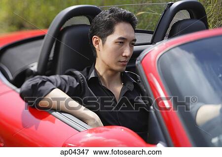 Stock Photo - Man driving red convertible car. Fotosearch