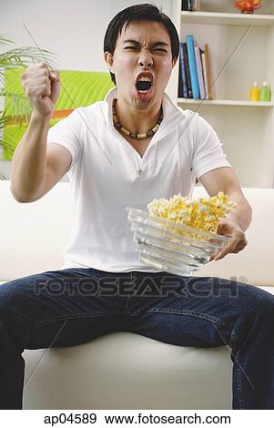 Man holding bowl of popcorn, making a fist View Large Photo Image Stock Photo - Man holding bowl of popcorn, making a fist. Fotosearch